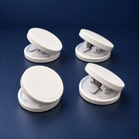 Four white round Crease-Lock weighted clips on a navy background